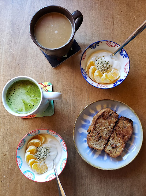 Coffee, matcha, vegan yogurt bowls topped with orange slices and hemp hearts, and vegan banana bread