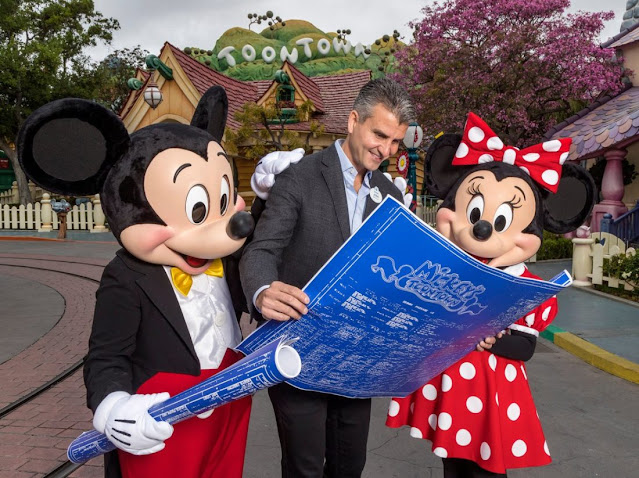 man with Mickey and Minnie holding blueprint