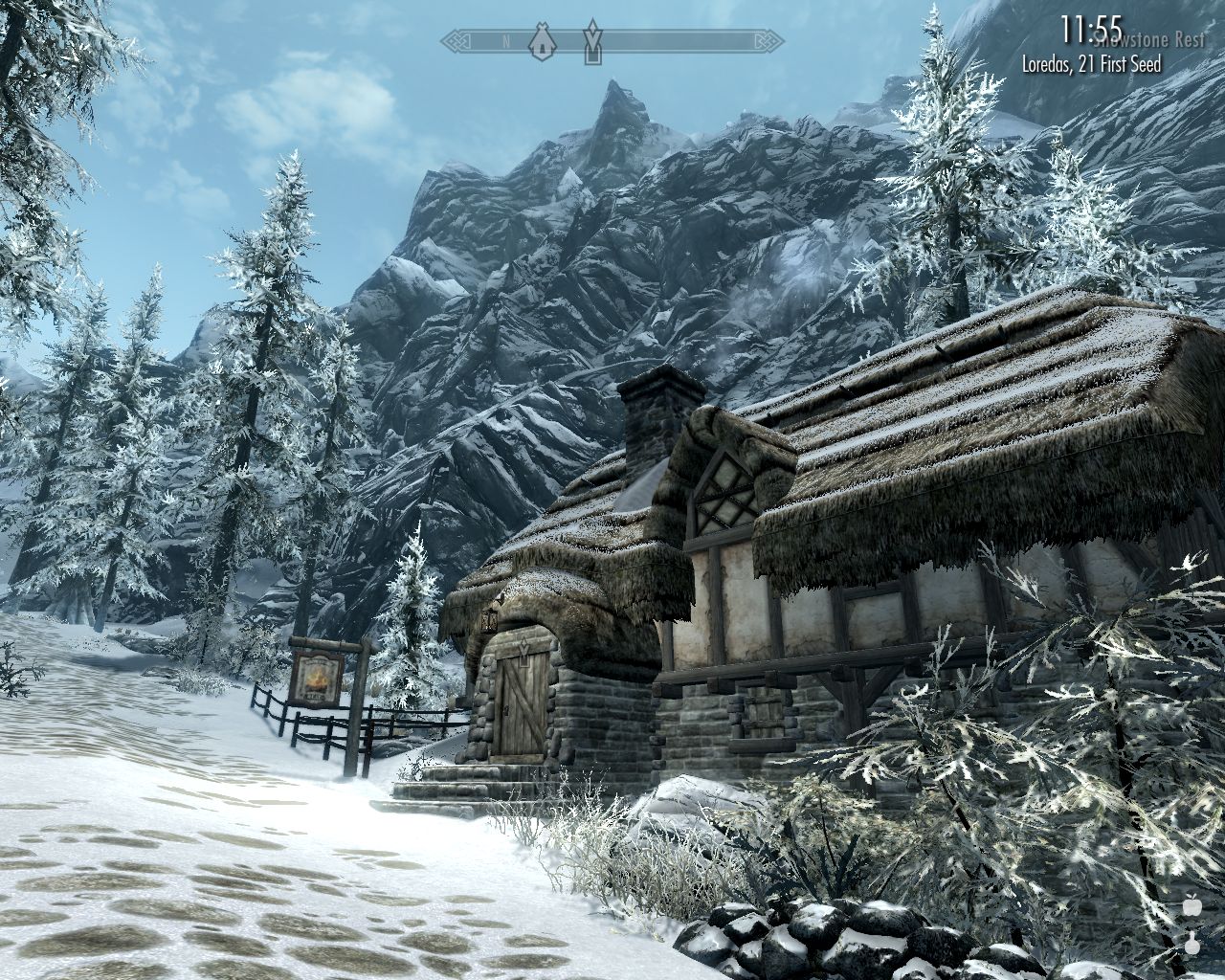 snowy uphill road leads past to an inn in a small stone house with a thatched roof at the foot of rocky mountains