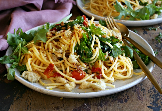 Recipe for a pasta dish with arugula, confit tomatoes and crispy torn bread.
