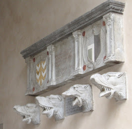 A set of stone gargoyles on the wall above Palazzo della Ragione's covered staircase