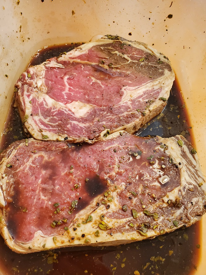 these are ribeye steaks in the marinade to grill