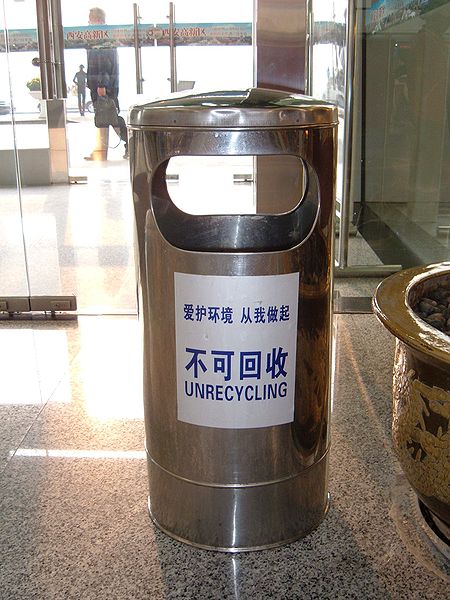 a sign on a trash can with Chinese characters and an English translation "Unrecycling"