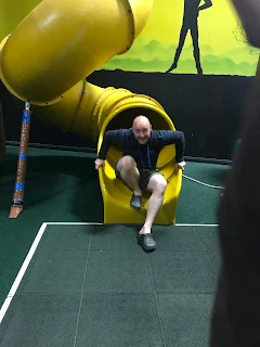 man coming out slide indoor play area