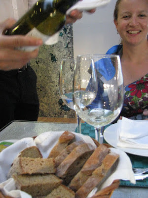 cesta de pão. mulher sorrindo e alguém servindo um copo de vinho
