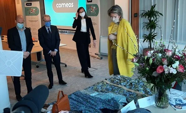 Queen Mathilde wore a yellow coat from Belgian designer Edouard Vermeulen of Natan, and a yellow satin print blouse from Dries van Noten