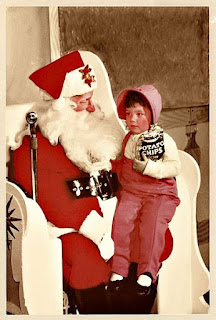 An old photo from the mid 1950s of a little girl in pink snow leggings on Santa's knee.