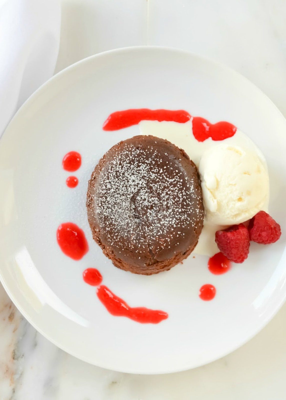 Molten Chocolate Lave Cake is a delicious chocolate cake with a warm fudge center. Easy to make dessert recipe and great with a scoop of vanilla ice cream and drizzle of raspberry sauce from Serena Bakes Simply From Scratch. 