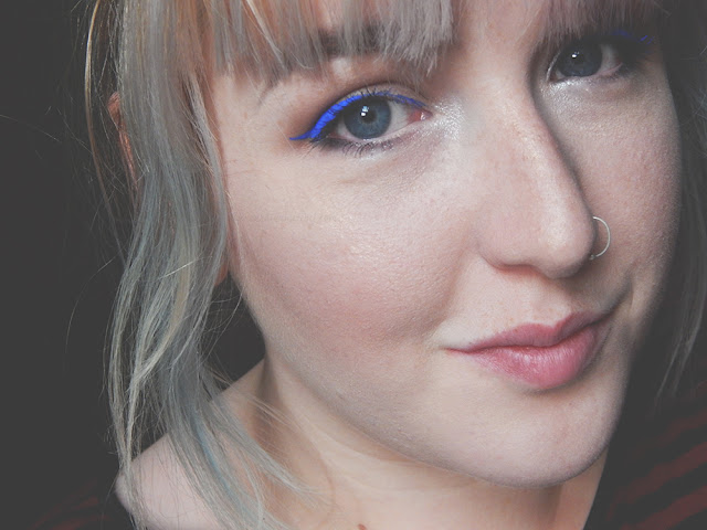 Girl smiling with bright blue winged eyeliner
