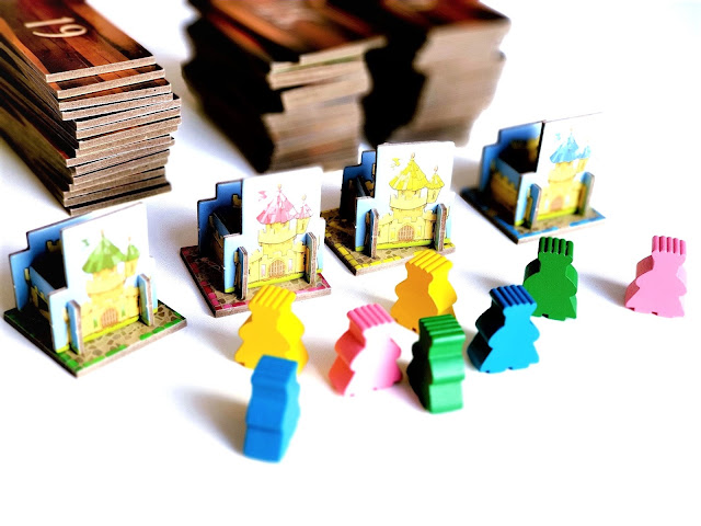 Kingdomino gra recenzja , na zdjęciu zbliżenie na kolorowe meeple, trójwymiarowe zamki 