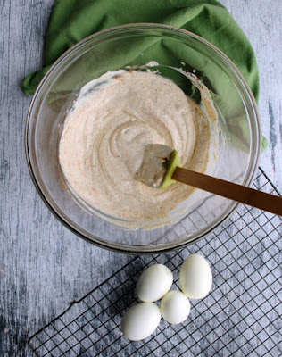 bowl of cream dressing for pasta salad with cooling rack and hard boiled eggs nearby