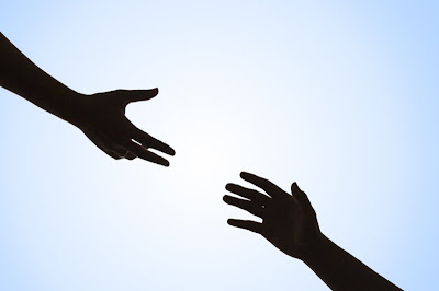 two hands reaching for each other with a blue sky as the background