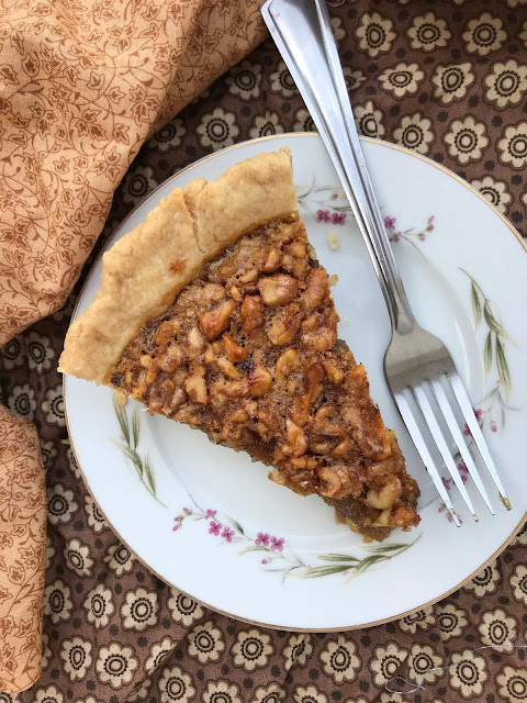Slice of honey walnut pie on a pie plate with a fork.