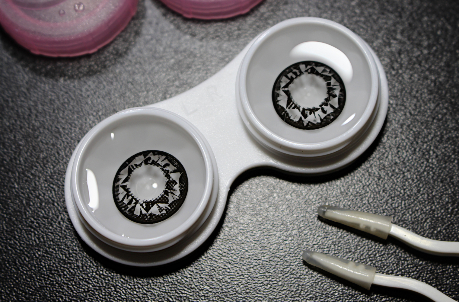 a close-up of a pair of black diamond circle lenses by Geo Medical on top of a black table