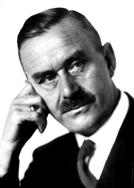 black-and-white photo of a serious-looking mustached man with a full head of hair, leaning his head on the knuckles of his right hand in an almost-coy pose