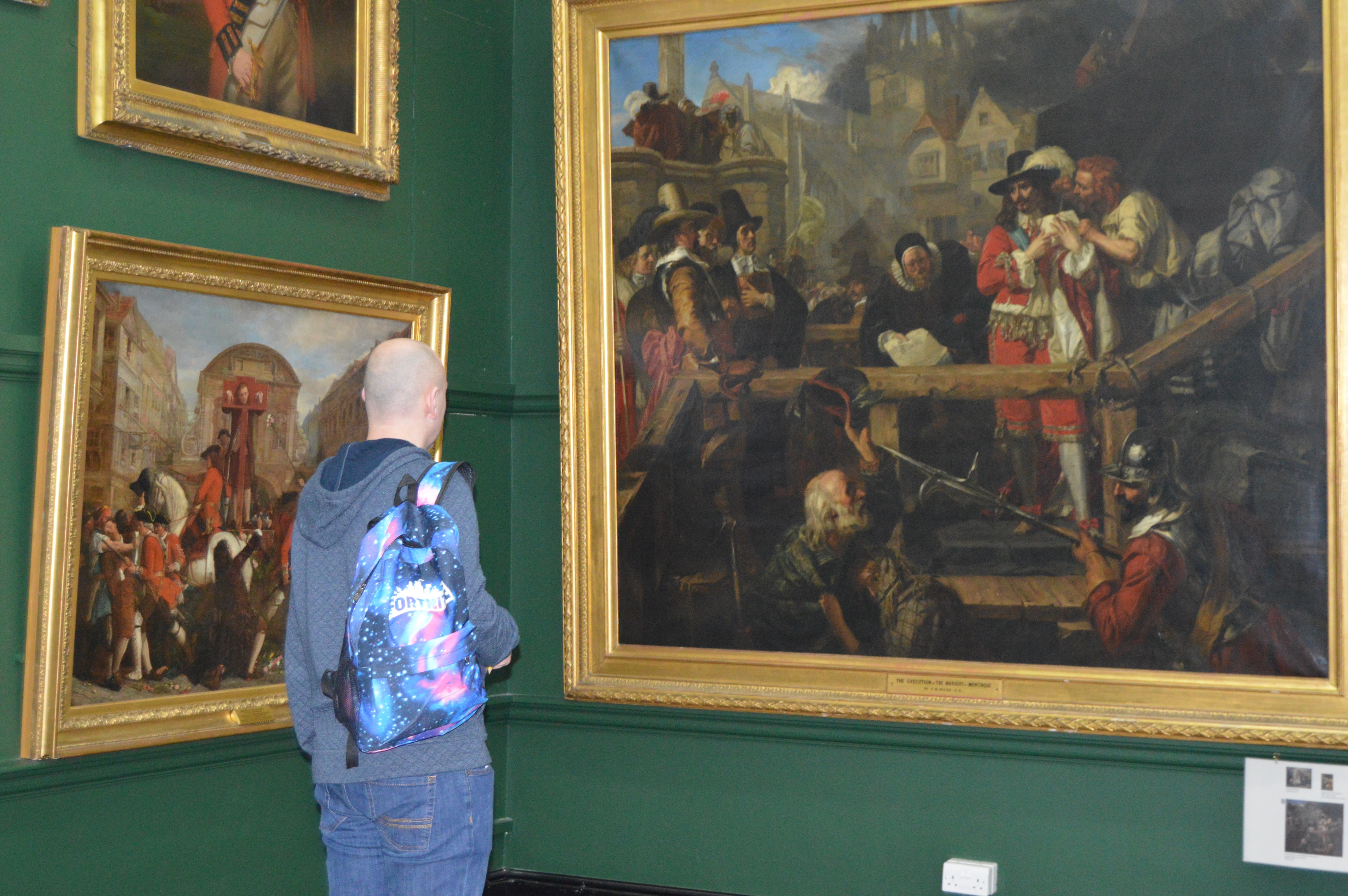 Man looking at paintings on a wall