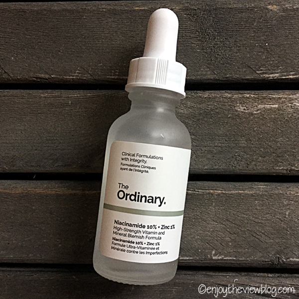 A bottle of Niacinamide 10% + Zinc 1% Serum from The Ordinary lying on a wooden table