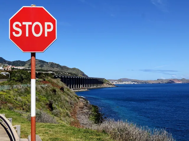 Stop sign with view of Funchal airport runway on stilts behind it in Madeira