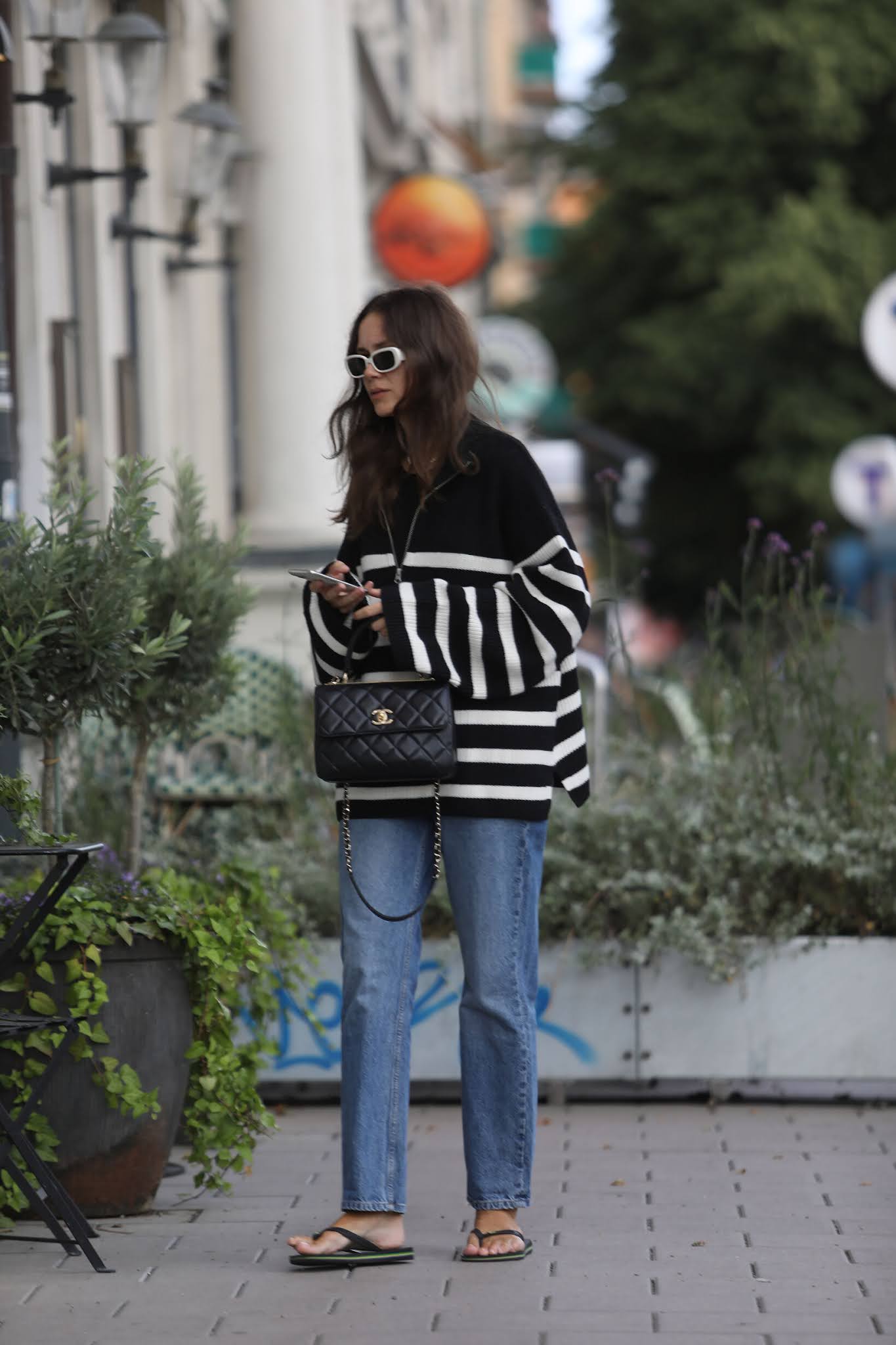 Best Striped Half-Zip Sweaters — Caroline Blomst of Carolines Mode winter outfit in a striped pullover knit, jeans, Chanel bag, and flip-flops