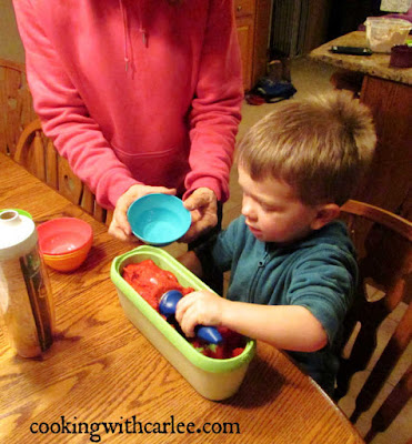 scooping frozen raspberry sorbet Little Dude taking a scoop of raspberry sorbet and putting it in bowl