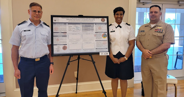 Three people standing next to a research board.
