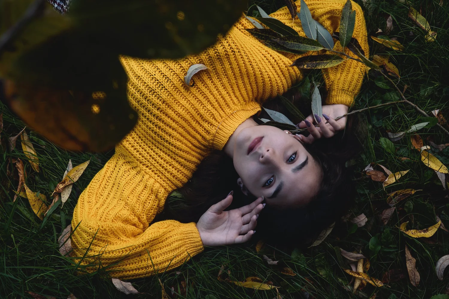 woman in sweater is laying on the grass