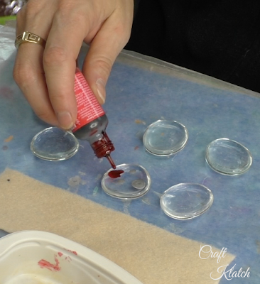 Red alcohol ink being dripped onto the flat side of a glass gem