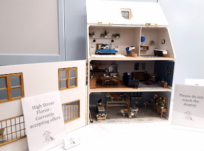1/12 scale three-story dolls' house with florist shop on the ground flooe, lounge and kitchen on the first and bedroom and bathroom in the attic space.