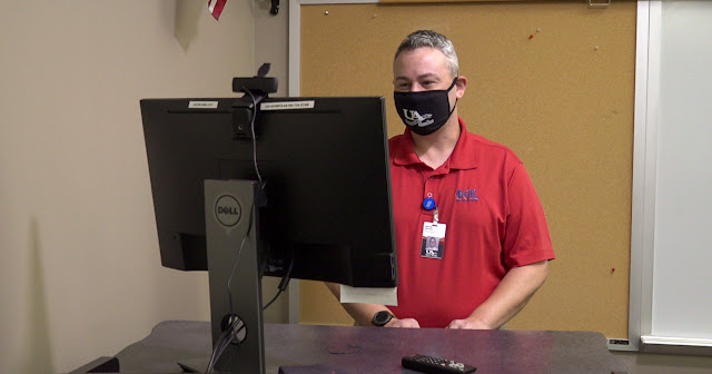 Faculty member stands at a computer station while instructing a synchronous course