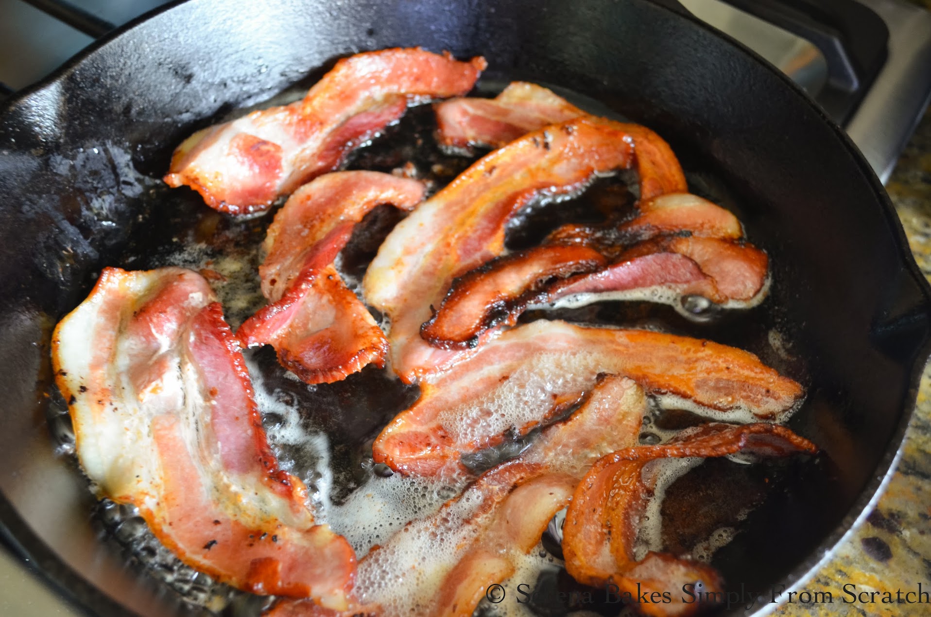 Bacon frying in a large cast iron frying pan.