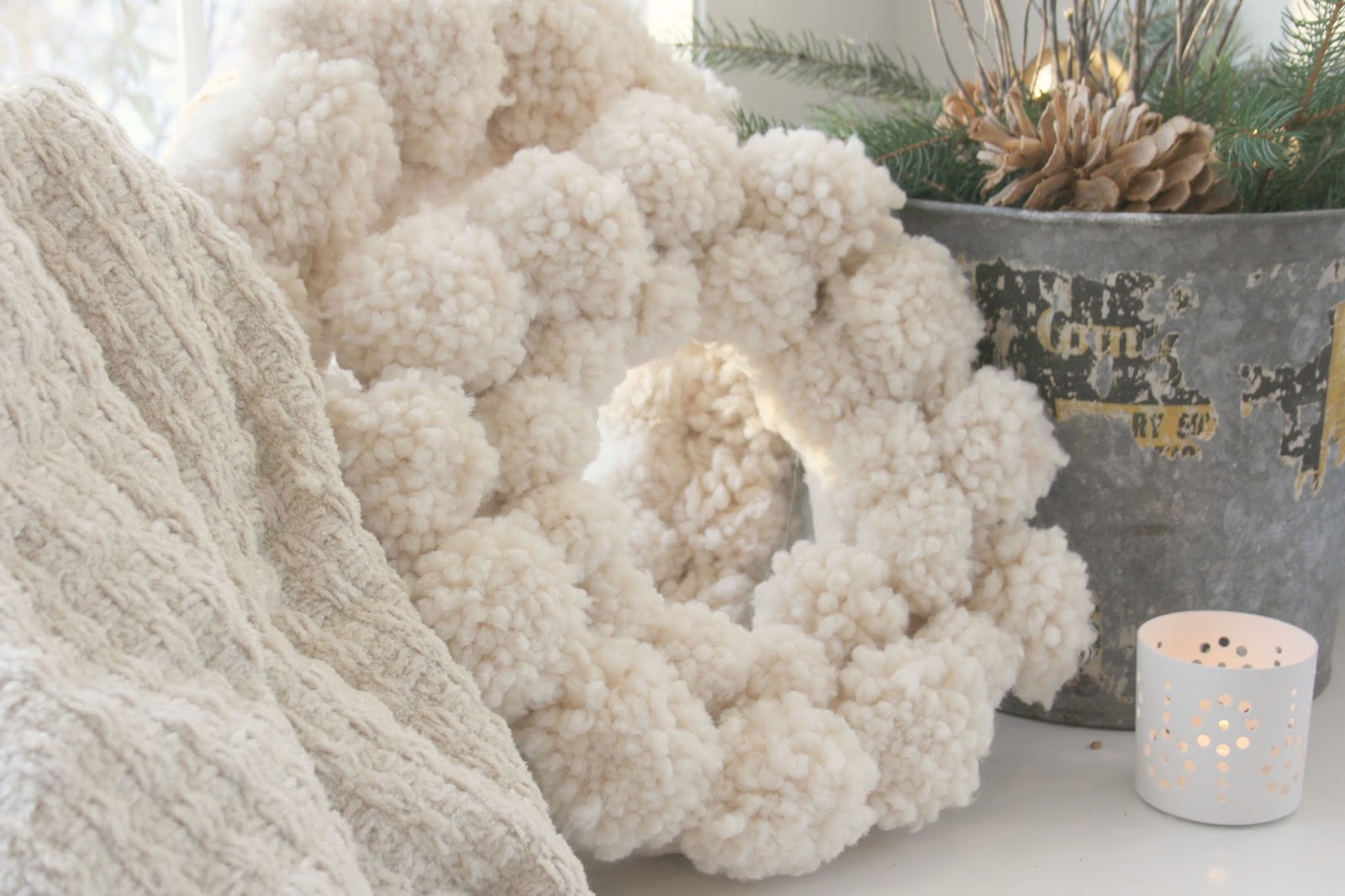 White holiday wooly pom pom wreath and galvanized bucket with fresh greenery