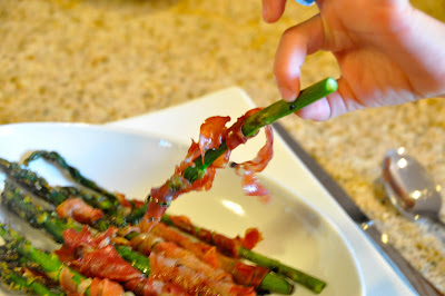 prosciutto wrapped around asparagus being picked out of a bowl
