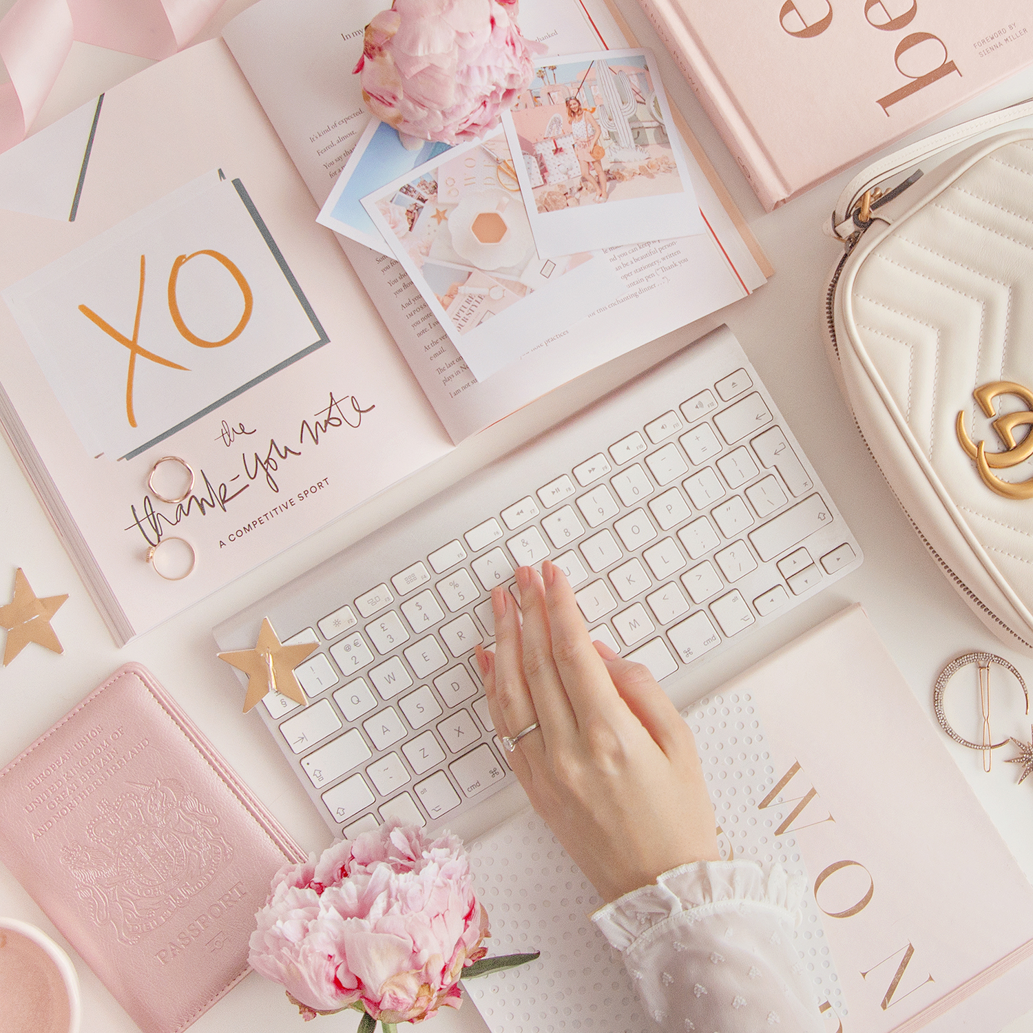 Flat lay image of a desk setup with pink accessories and flowers