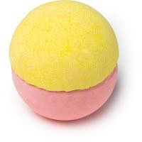 A yellow semi spherical bath bomb and a pink semi spherical bath bomb sandwiched together on a bright background 