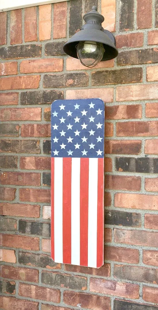 Wooden American flag hanging on brick wall