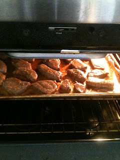 Chopped steak being cooked in the oven on a baking sheet.