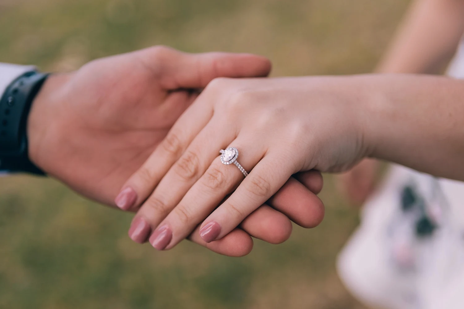 man holds womans hands and she is wearing engagement ring