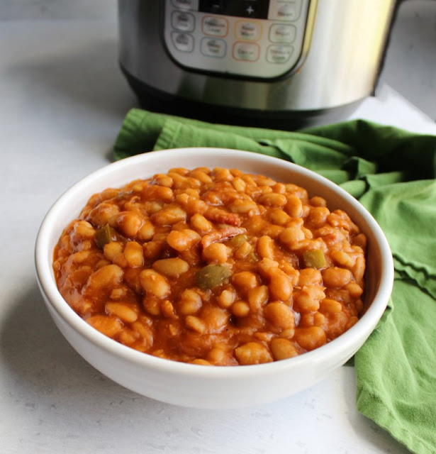 Baked beans are a classic side dish for good reason. This recipe flavors delicious baked beans with maple and bacon. They start with dried beans and can still be made in a couple of hours with the help of a pressure cooker. big bowl of maple bacon baked beans in front of instant pot