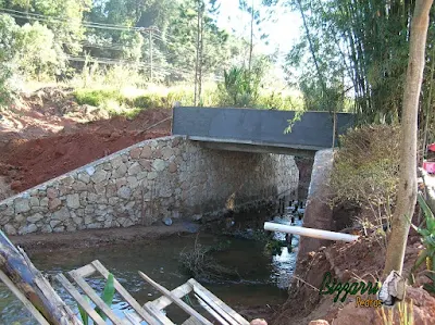 Construção do muro de pedra com pedra bruta para a base da construção da ponte de concreto na entrada da empresa em Atibaia-SP.