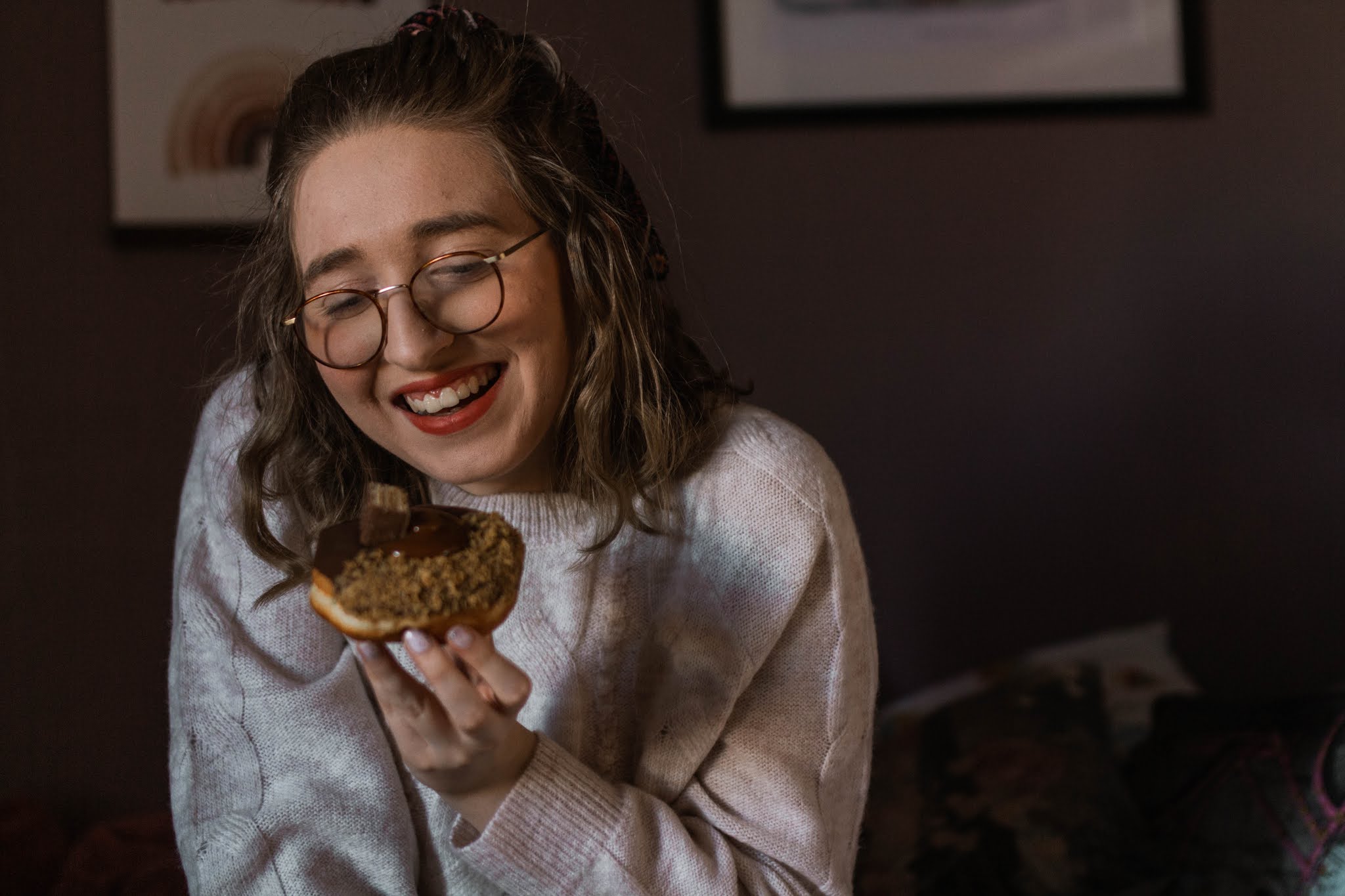 girl smiling while holding a chocolate donut