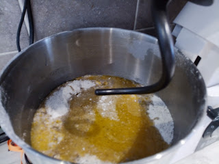 The bowl of ingredients sitting on the stand with a dough hook in them.