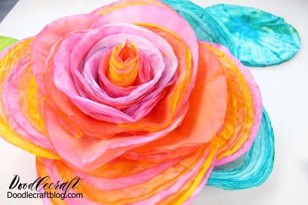 How to make a rose out of coffee filters dyed with food coloring bright colors, stapled together in layers.