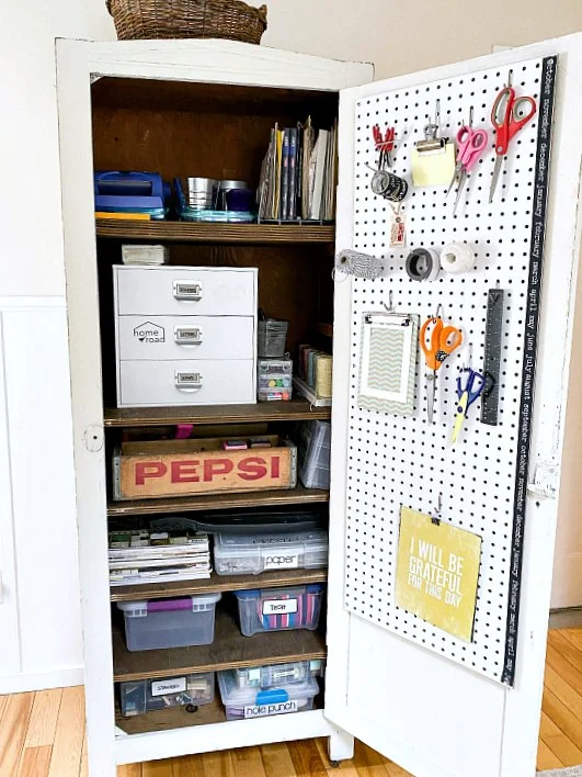 A craft cabinet with a peg board door