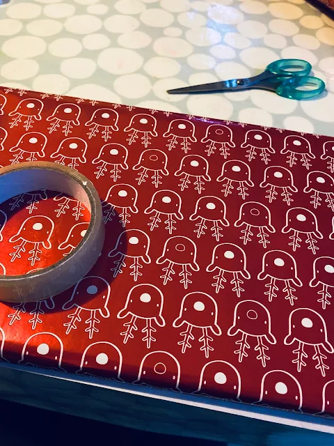 Red shiny reindeer wrapping paper on a present, sellotape and scissors