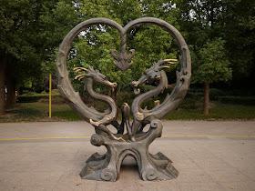 sculpture of two dragons with intertwined tails forming a heart shape
