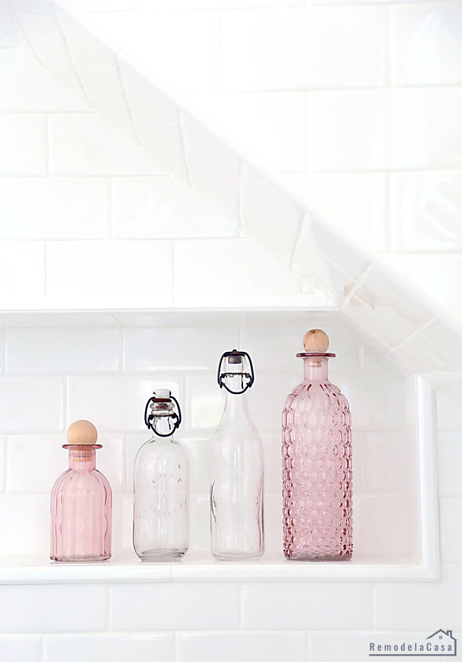 vintage clear and pink glass bottles on shower niche