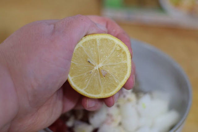 Lemon juice being squeezed into the bowl.