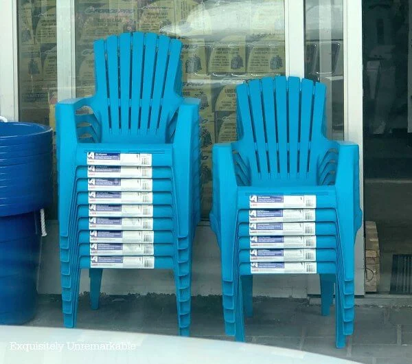 Stacks of blue Plastic Adirondack Chairs in front of a hardware store