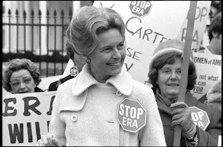 Schlafly wearing "STOP ERA" button, standing in front of protesters with signs