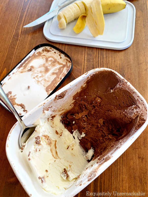 Ice cream container and sliced banana on a cutting board